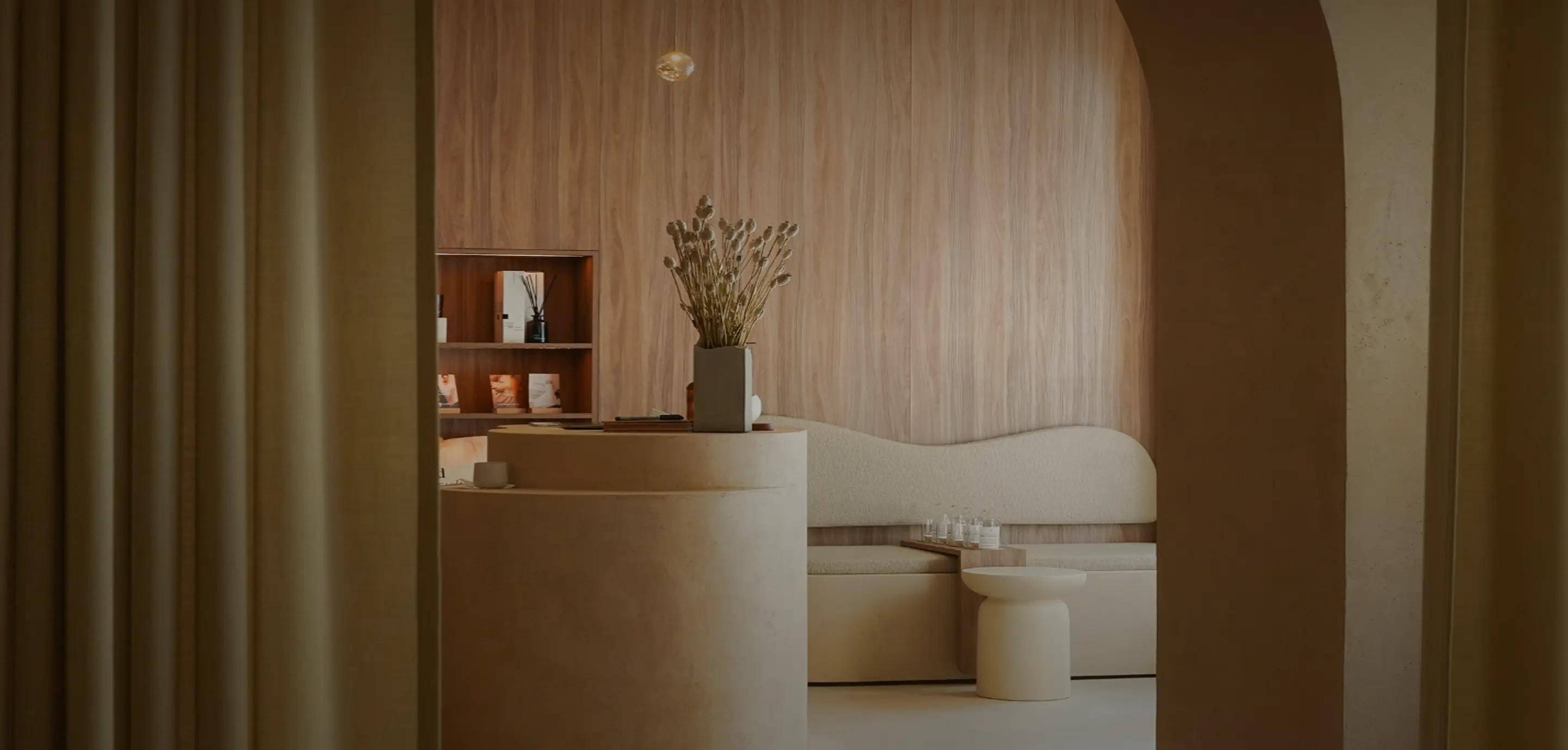 Elegantes, minimalistisches Interieur eines Soulhouse Studios mit runden Möbeln, einer Vase mit Trockenblumen und einer Holzverkleidung an der Wand.