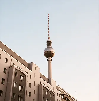 Fernsehturm Berlin über Wohngebäuden bei klarem Himmel.