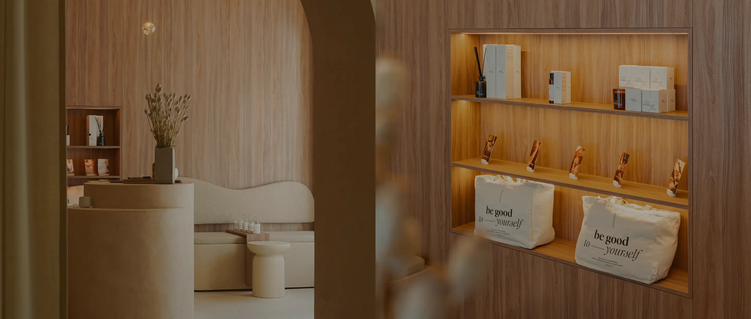 Modernes Soulhouse Studio mit runden beige Möbeln, einer Bank, einem kleinen Tisch und einem hölzernen Regal mit dekorativen Taschen und Produkten.