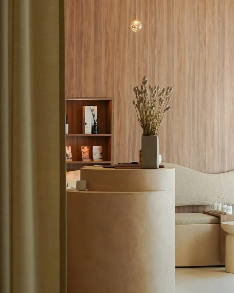 Minimalistisches Soulhouse Studio mit runden beigefarbenen Möbeln, Trockenblumen in einer Vase und Holzpaneelen an der Wand.