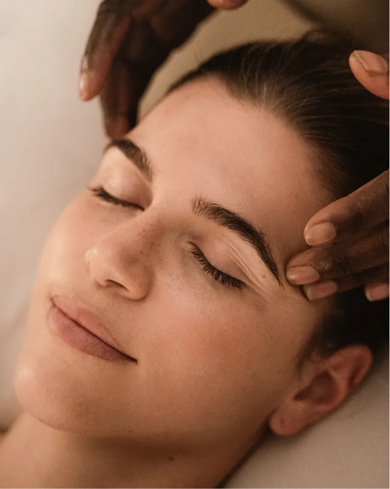 Frau mit geschlossenen Augen erhält eine entspannende Kopfmassage.