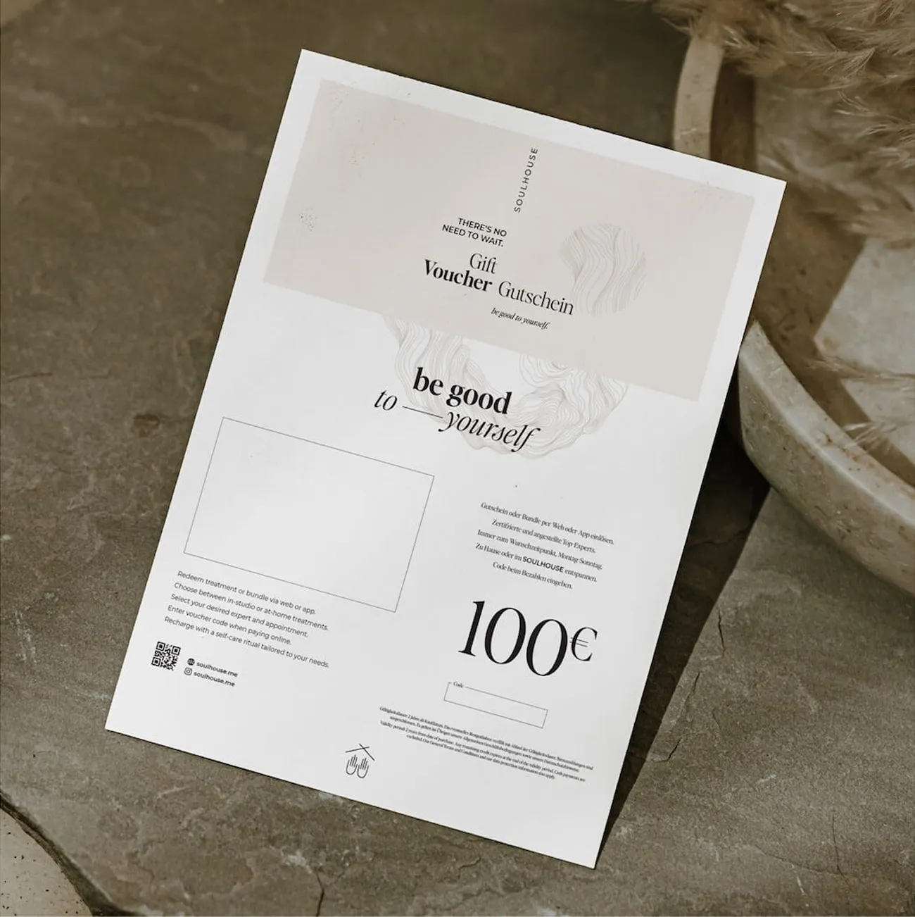 Geschenkgutschein im Wert von 100 Euro von Soulhouse mit dem Schriftzug ‚be good to yourself‘ auf steinernem Untergrund.