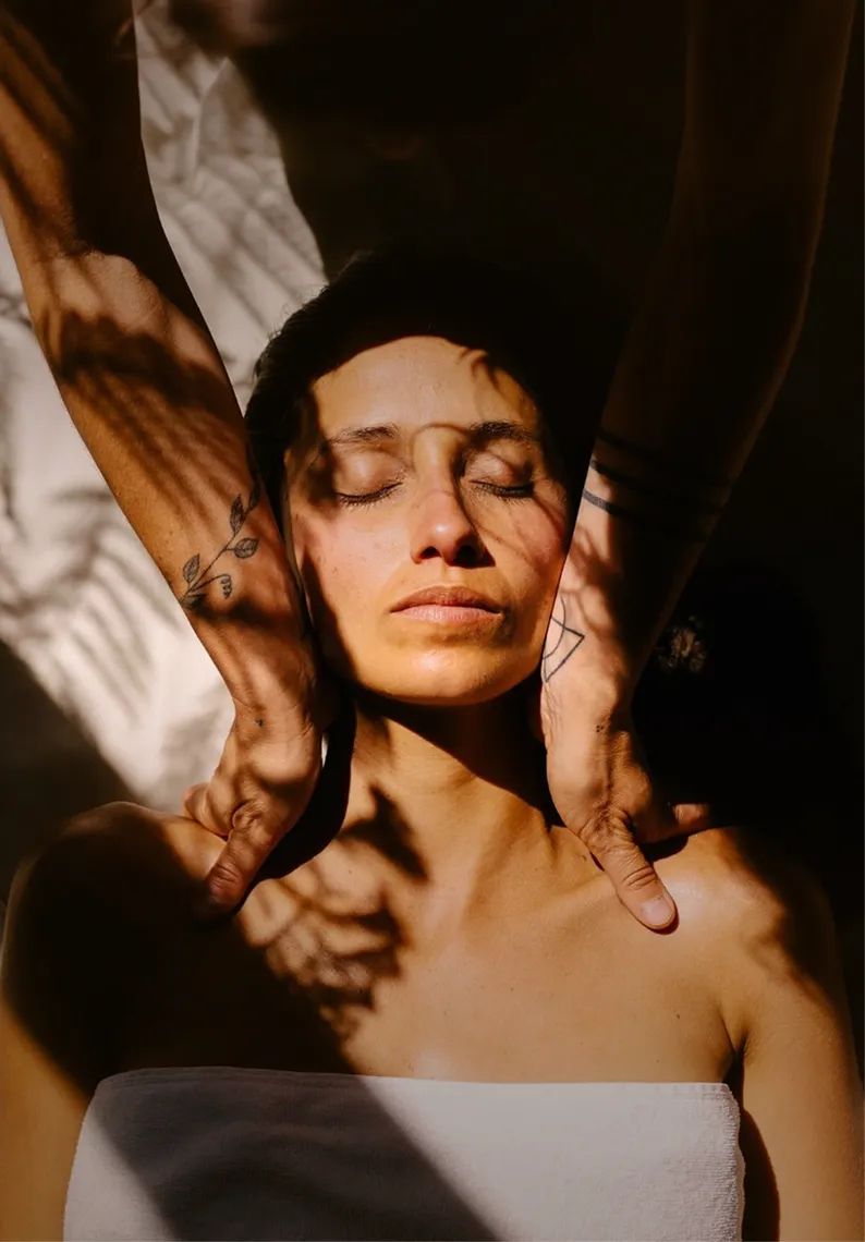 Frau entspannt mit geschlossenen Augen, während Hände mit  ihre Schultern massieren.