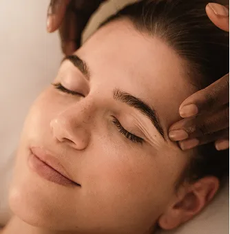 Eine Frau entspannt mit geschlossenen Augen, während einer entspannten Wellnessmassage.