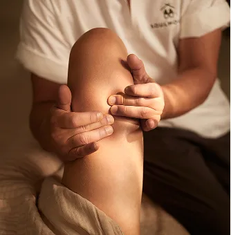 Therapeutin führt eine Tiefengewebsmassage an einem Oberschenkel durch.