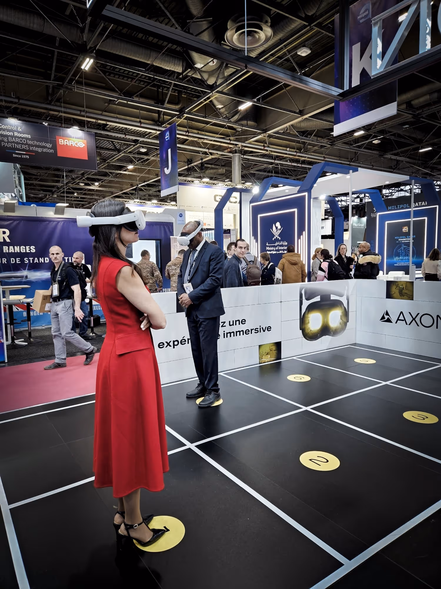Two soldiers in tactical gear aiming rifles behind a protective digital shield as three drones fly in dark smoky sky.