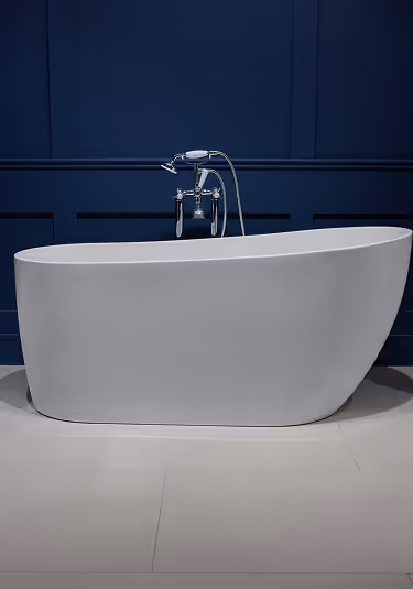 Modern white freestanding bathtub with chrome faucet against a dark blue paneled wall.