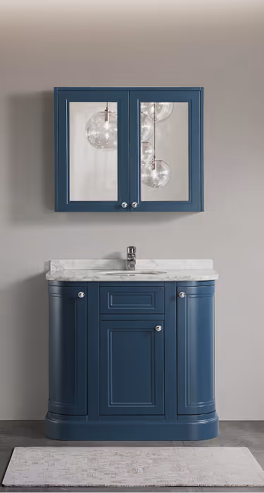 Navy blue bathroom vanity with marble countertop below a matching wall cabinet with mirrored doors and spherical hanging lights reflected.