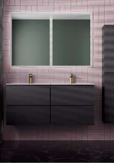 Modern bathroom vanity with two black drawers, two gold faucets, and a large rectangular backlit mirror on pink tiled wall.