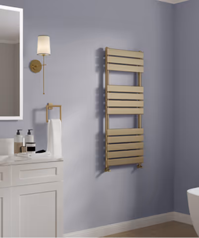 Modern bathroom with grey walls, a white vanity with toiletries, a wall-mounted sconce light, and a gold towel warmer.