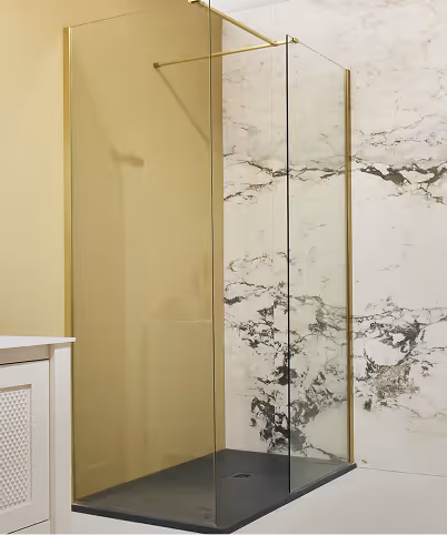 Minimalist walk-in shower with glass panels, gold frame, dark base, and white marble wall with gray veining.