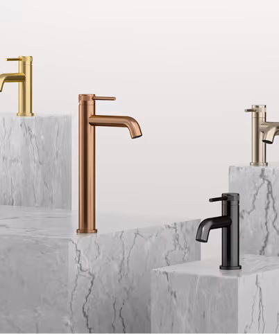 Four modern bathroom faucets in gold, copper, brushed nickel, and matte black finishes displayed on white marble pedestals.