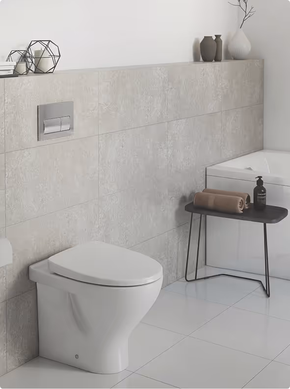 Modern bathroom with a white toilet, beige tiled wall, and a corner bathtub next to a small black table holding rolled towels and a soap dispenser.
