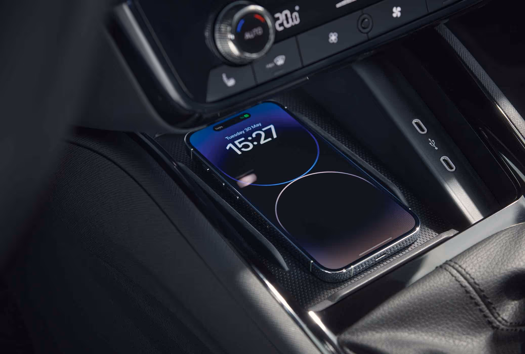 Eine Nahaufnahme zeigt die Phonebox in der Mittelkonsole eines Škoda Scala Balance, in der ein Smartphone kabellos geladen wird. Auf dem Bildschirm des Telefons werden der Ladevorgang und die Uhrzeit angezeigt.