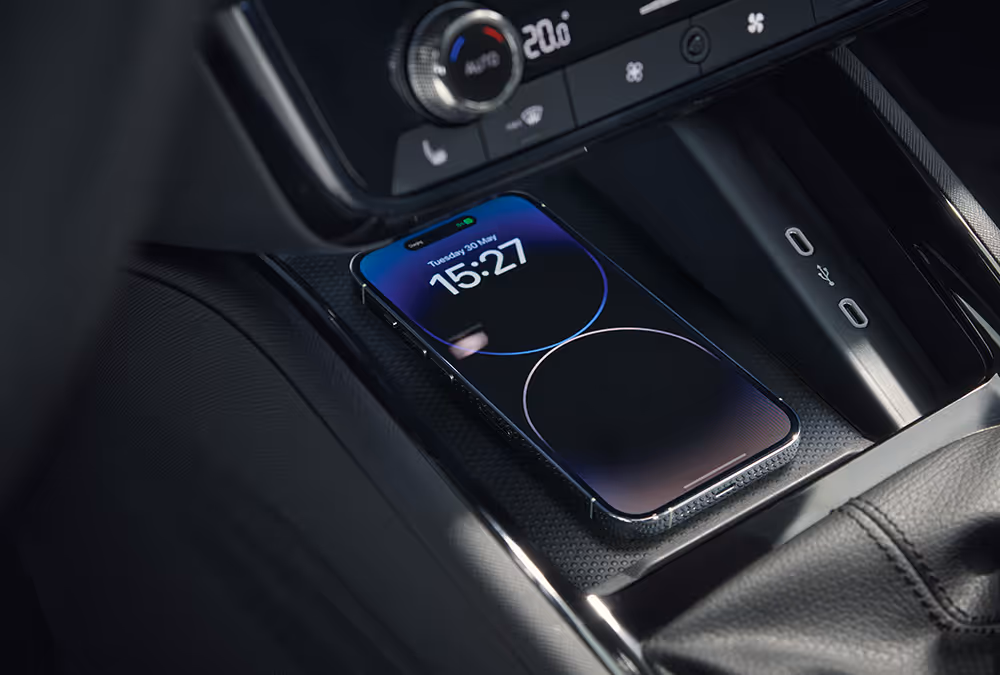 Eine Nahaufnahme zeigt die Phonebox in der Mittelkonsole eines Škoda Scala Balance, in der ein Smartphone kabellos geladen wird. Auf dem Bildschirm des Telefons werden der Ladevorgang und die Uhrzeit angezeigt.