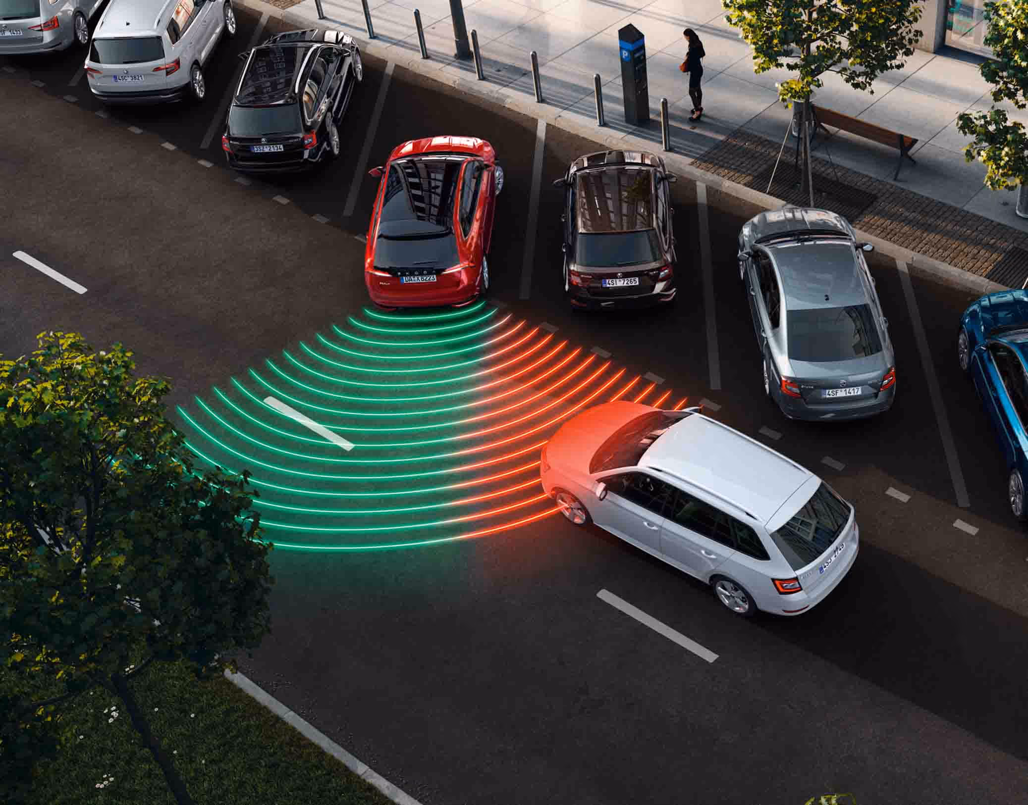Animation des Ausparkassistenten: Ein roter Škoda Scala Balance setzt rückwärts aus einer Parklücke aus, während sich von der Seite ein anderes Fahrzeug nähert. Leuchtende rote Linien visualisieren den Sensorbereich des Assistenten, der ein herannahende Auto erkennt und eine Warnung ausgibt.