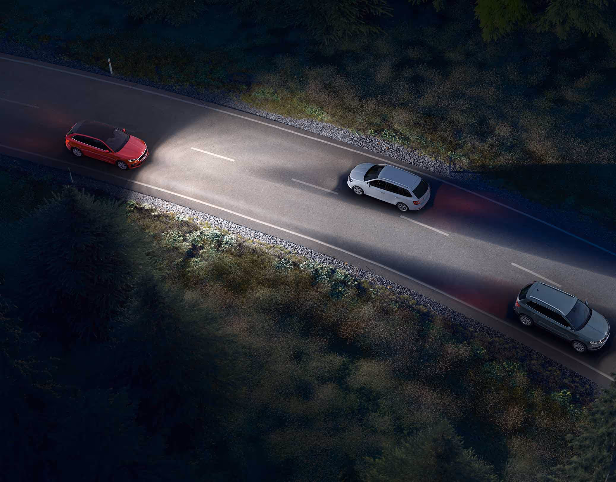 Animation des Dynamischen Fernlichtassistenten: Ein roter Škoda Scala Balance fährt nachts auf einer Landstraße und leuchtet die Fahrbahn mit Fernlicht aus. Das System erkennt entgegenkommende und vorausfahrende Fahrzeuge und blendet diese gezielt aus dem Lichtkegel aus, um eine Blendung zu vermeiden..