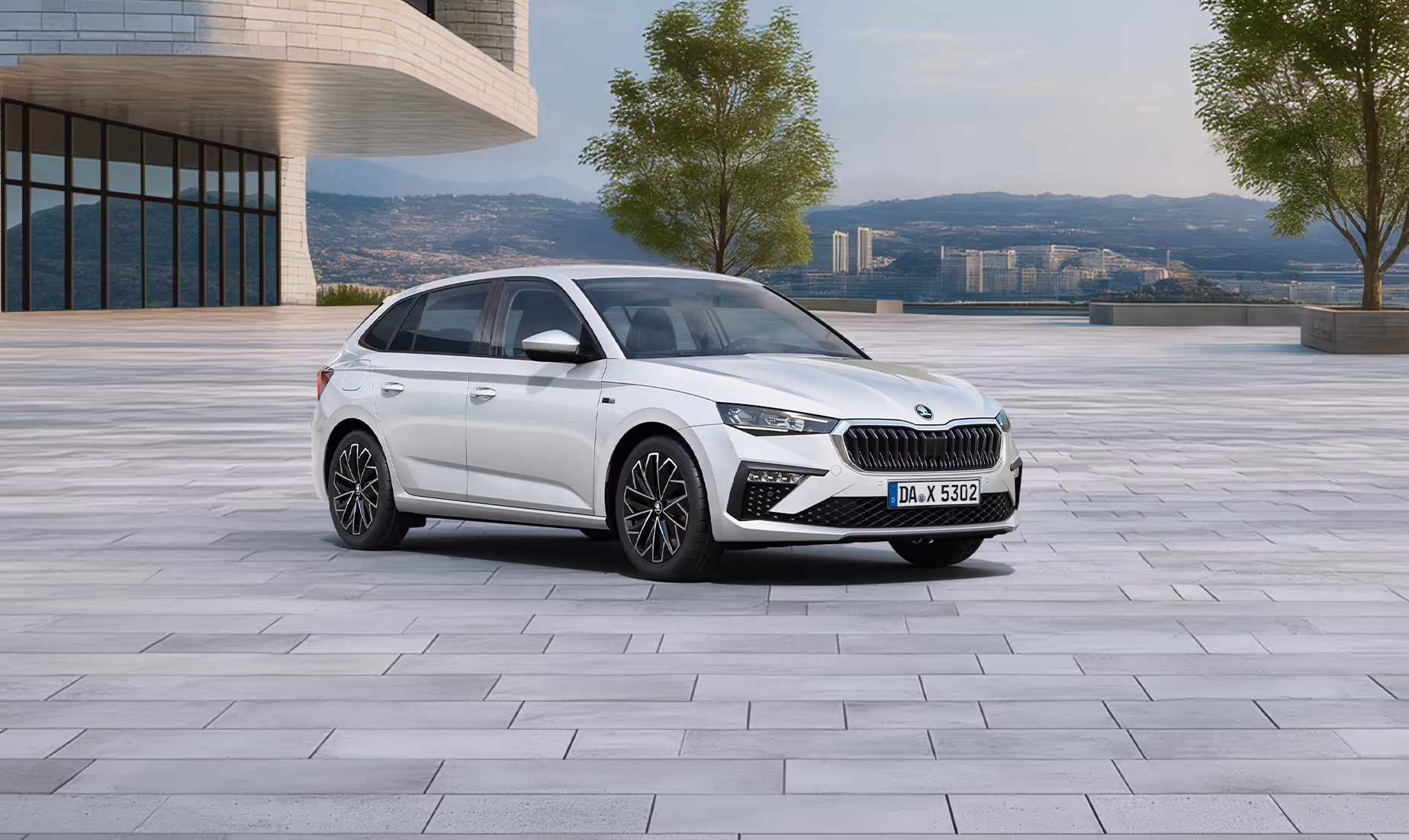 Front-Schrägansicht des Škoda Scala Balance in der Lackierung Moon-Weiß Perleffekt auf einem gepflasterten Platz vor einer Stadtkulisse in der Ferne. Das Fahrzeug ist mit dunklen, glanzgedrehten Leichtmetallfelgen ausgestattet. Im unteren Bildbereich weist ein grüner Störer auf einen Preisvorteil von 2.100 € sowie die inkludierte 5-Jahres-Garantie hin.