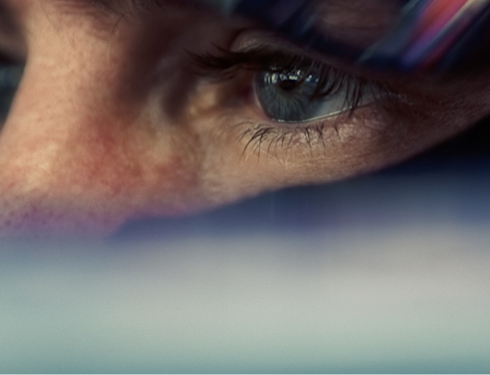 Close-up of a person's focused blue eye and surrounding skin with light reflections.