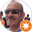 Smiling man with sunglasses and mustache in a circular avatar frame with an orange star badge.