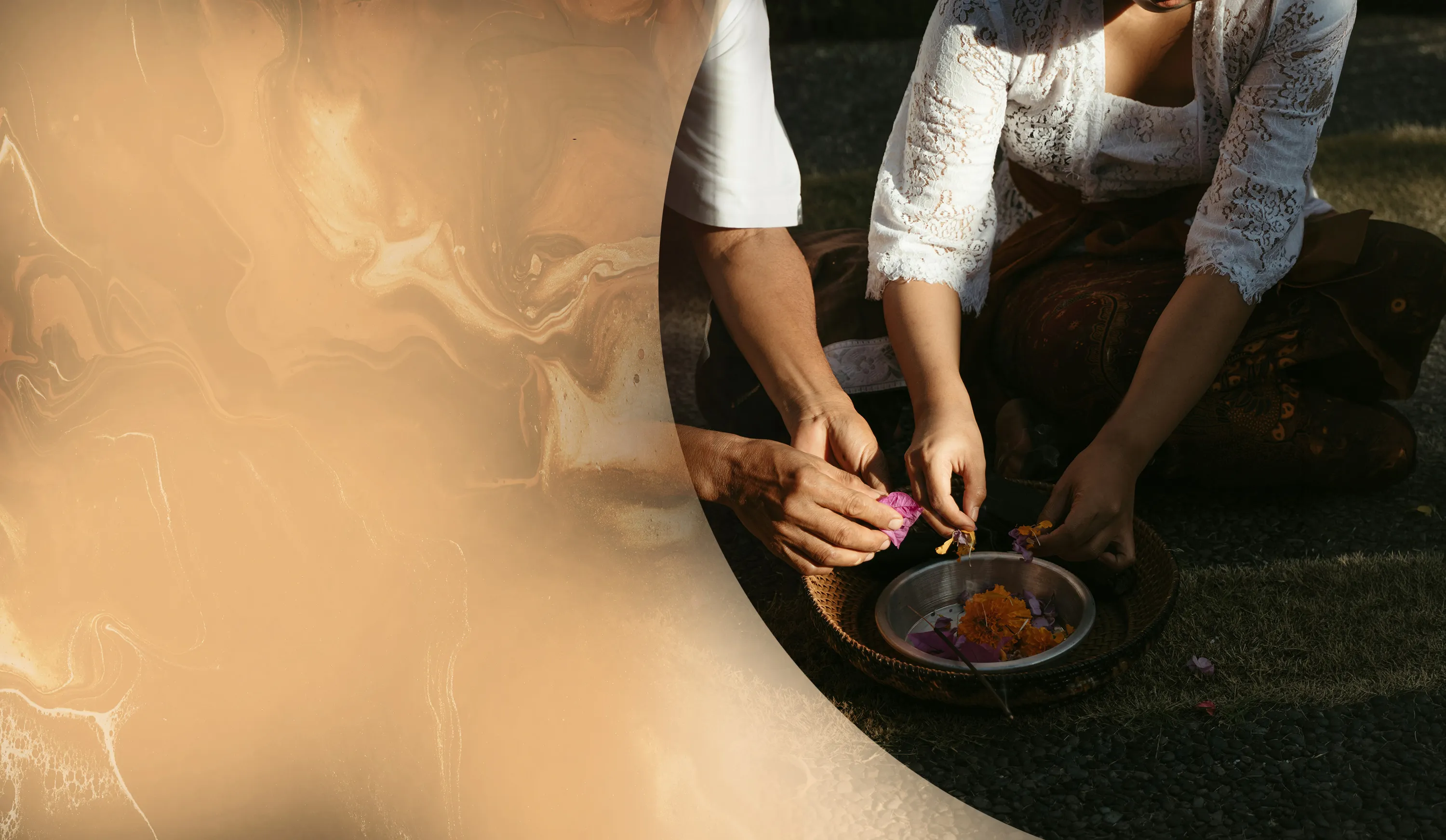 Two people dressed in traditional clothing arrange flower petals in a woven basket outdoors.
