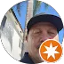 Close-up photo of a person wearing a dark cap with an orange star-shaped badge overlay in the bottom right corner.