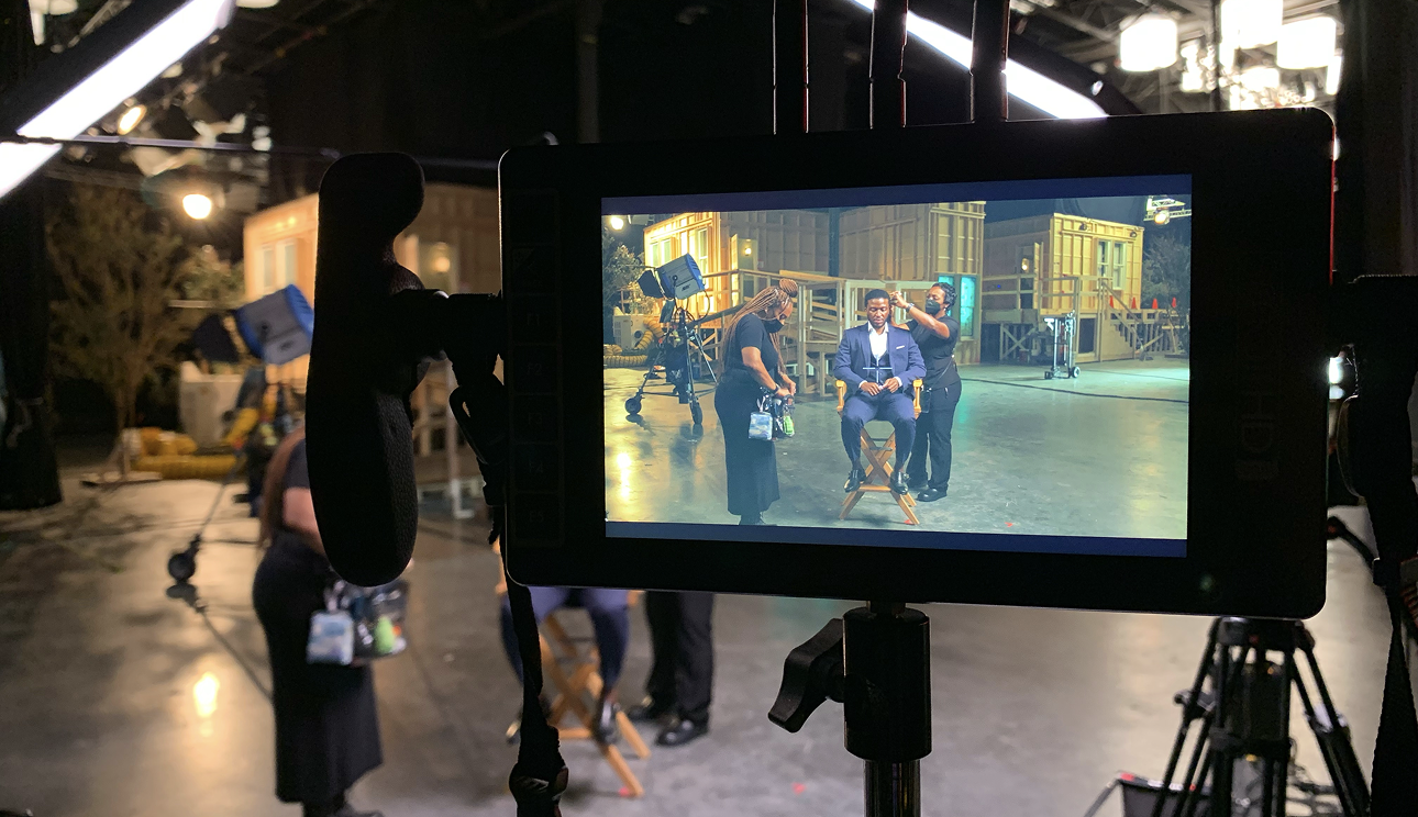 Camera monitor displaying talent being prepped by crew on a professional video production studio set