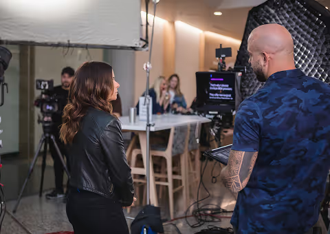 Director reviewing mobile video ad production setup with talent and crew on a professional studio set