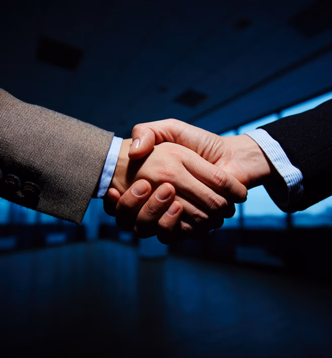 Two business professionals shaking hands in a corporate office setting