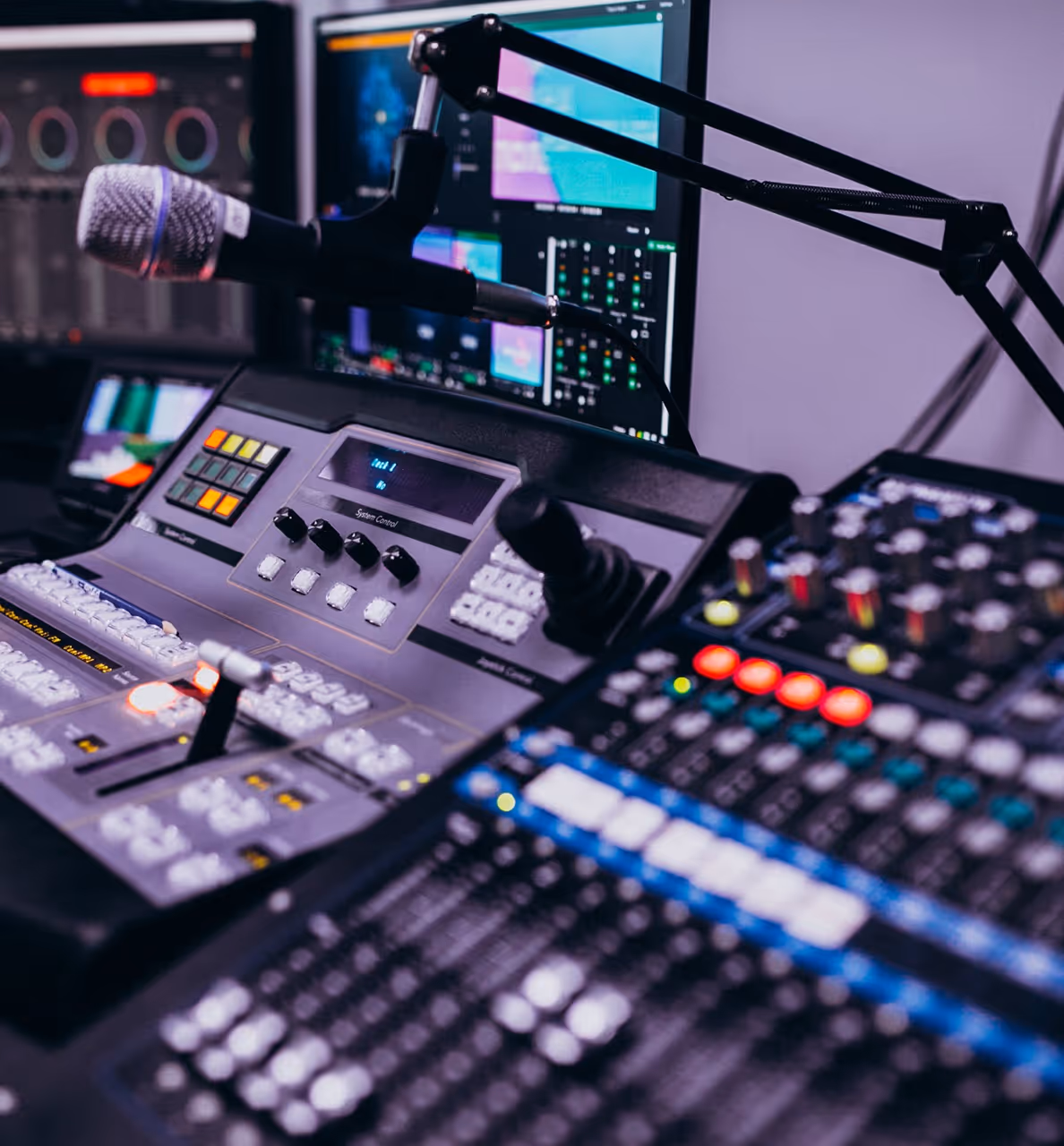 Broadcast mixing console and microphone setup in a control room.