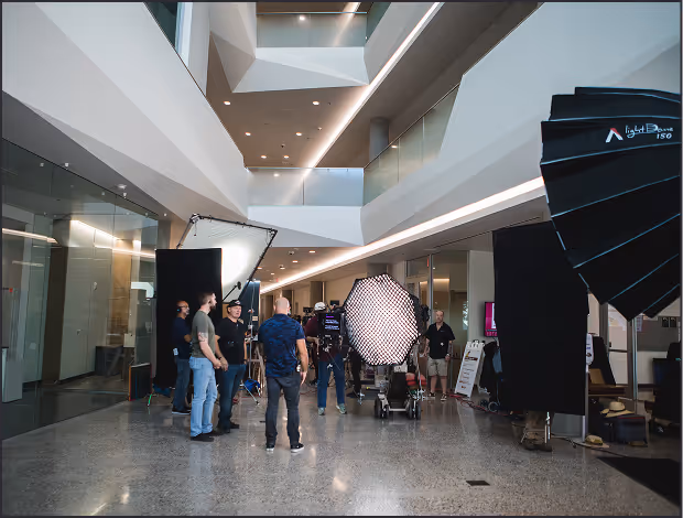 Corporate video production crew setting up professional lighting equipment inside a modern office building
