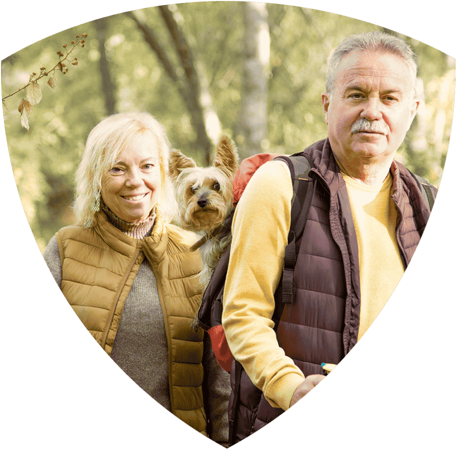 Older couple outdoors with small dog in backpack
