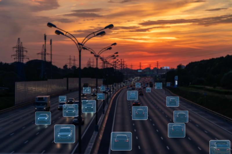 Young man in a dark hoodie thoughtfully looking at a computer screen in a dimly lit room.