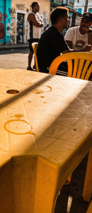 Objeto toroidal metálico com reflexos coloridos em tons de azul, laranja e roxo sobre fundo preto.