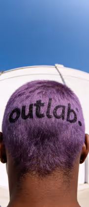 Parte traseira da cabeça com cabelo roxo e a palavra 'outlab.' raspada em preto.