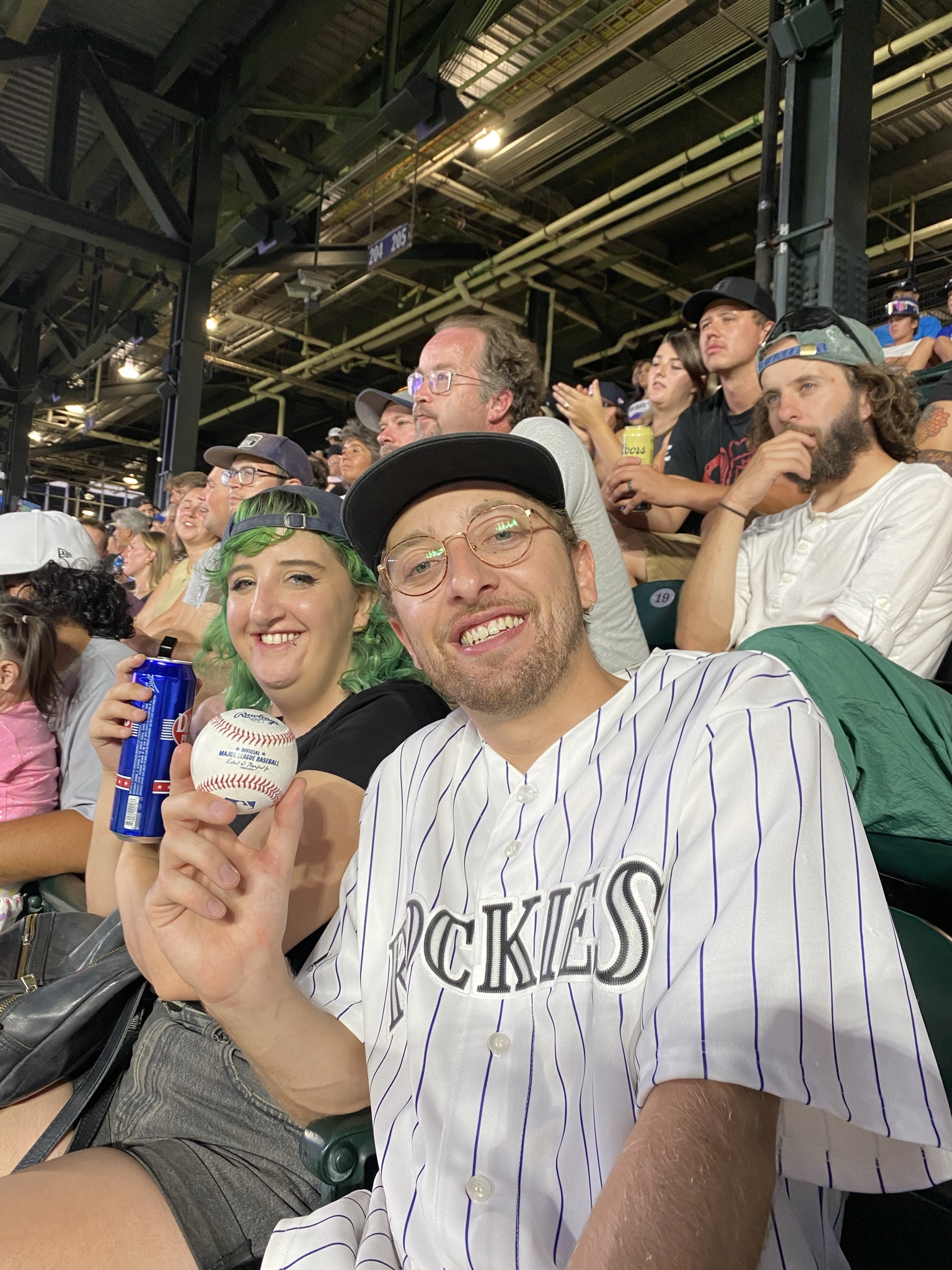 Dylan and a friend at a baseball game, holding up a baseball.