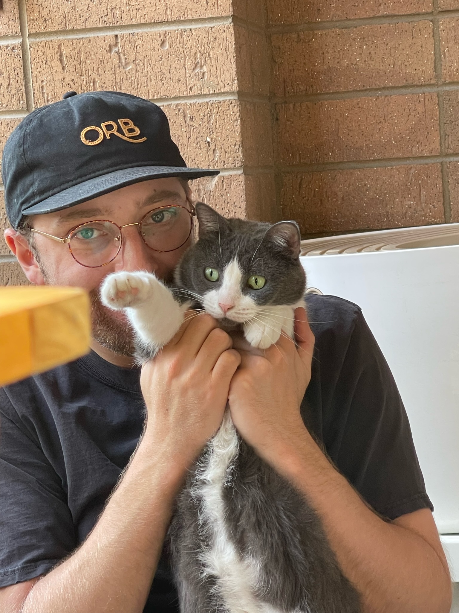 Dylan holding a gray-and-white cat with one paw raised.