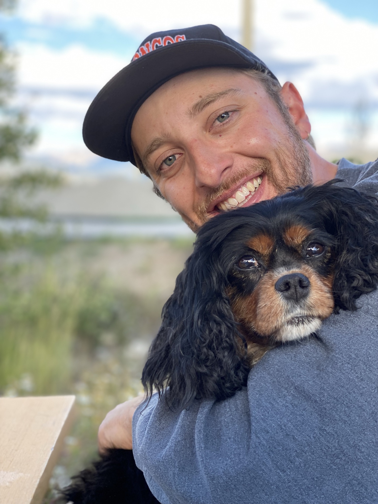 Dylan smiling while holding a black-and-tan dog.