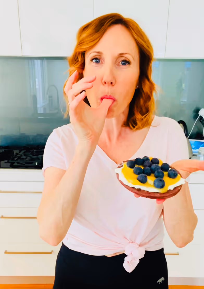 Joanna standing in her kitchen eating a sweet tart