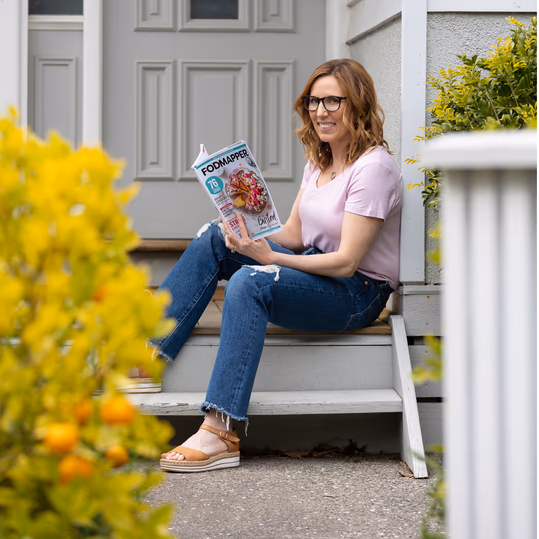 Joanna sitting on her doorstep reading the Fodmapper magazine