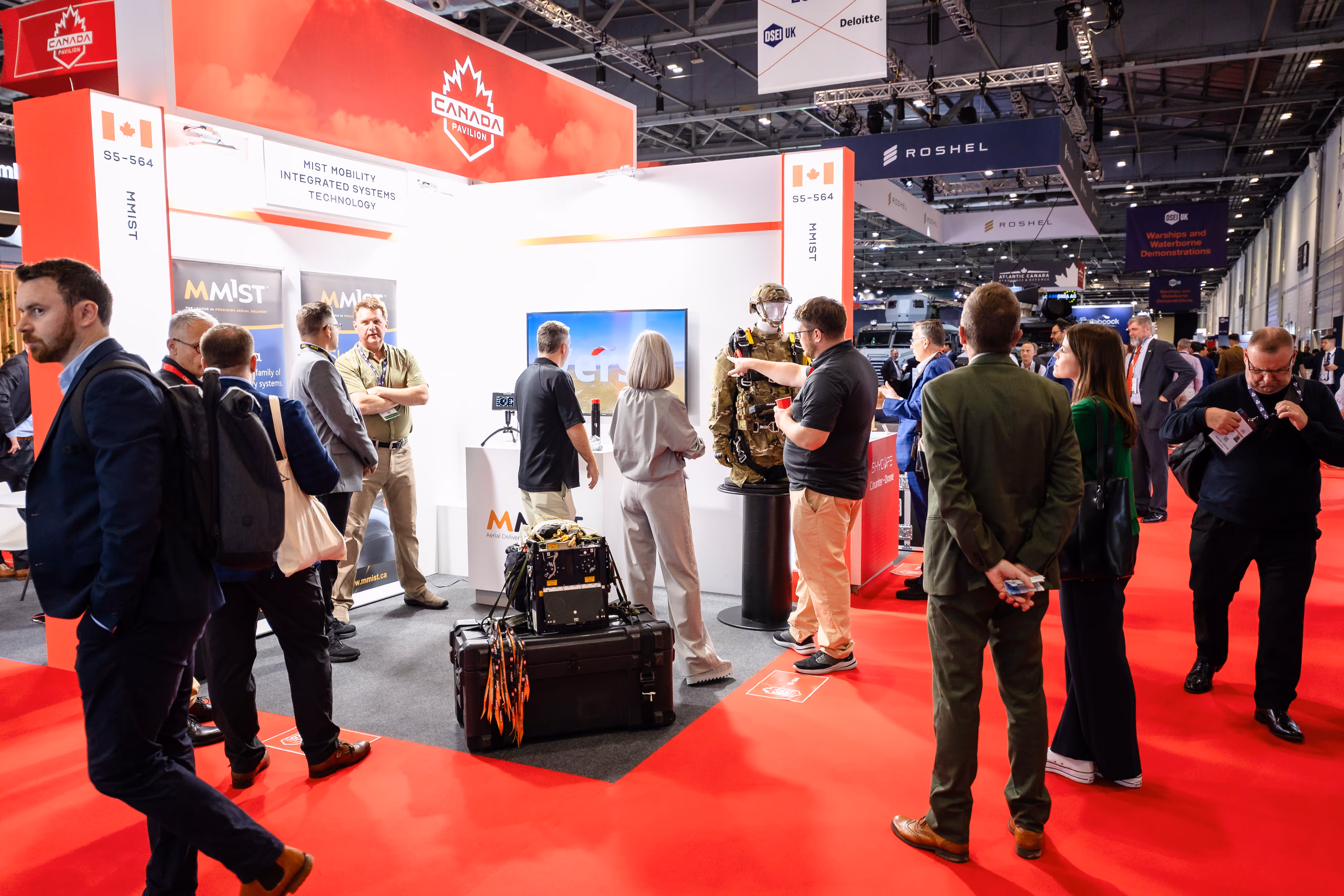 Busy CANSEC trade show floor with defence industry professionals networking among exhibition booths.