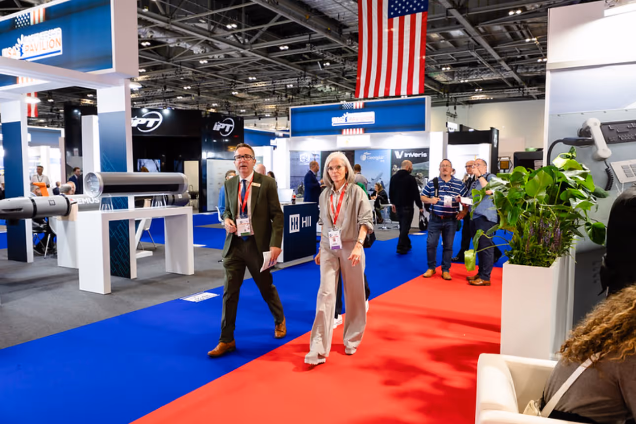 Busy CANSEC trade show floor with defence industry professionals networking among exhibition booths.
