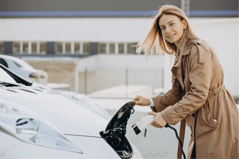 Woman looking at the camera while charging an EV car.
