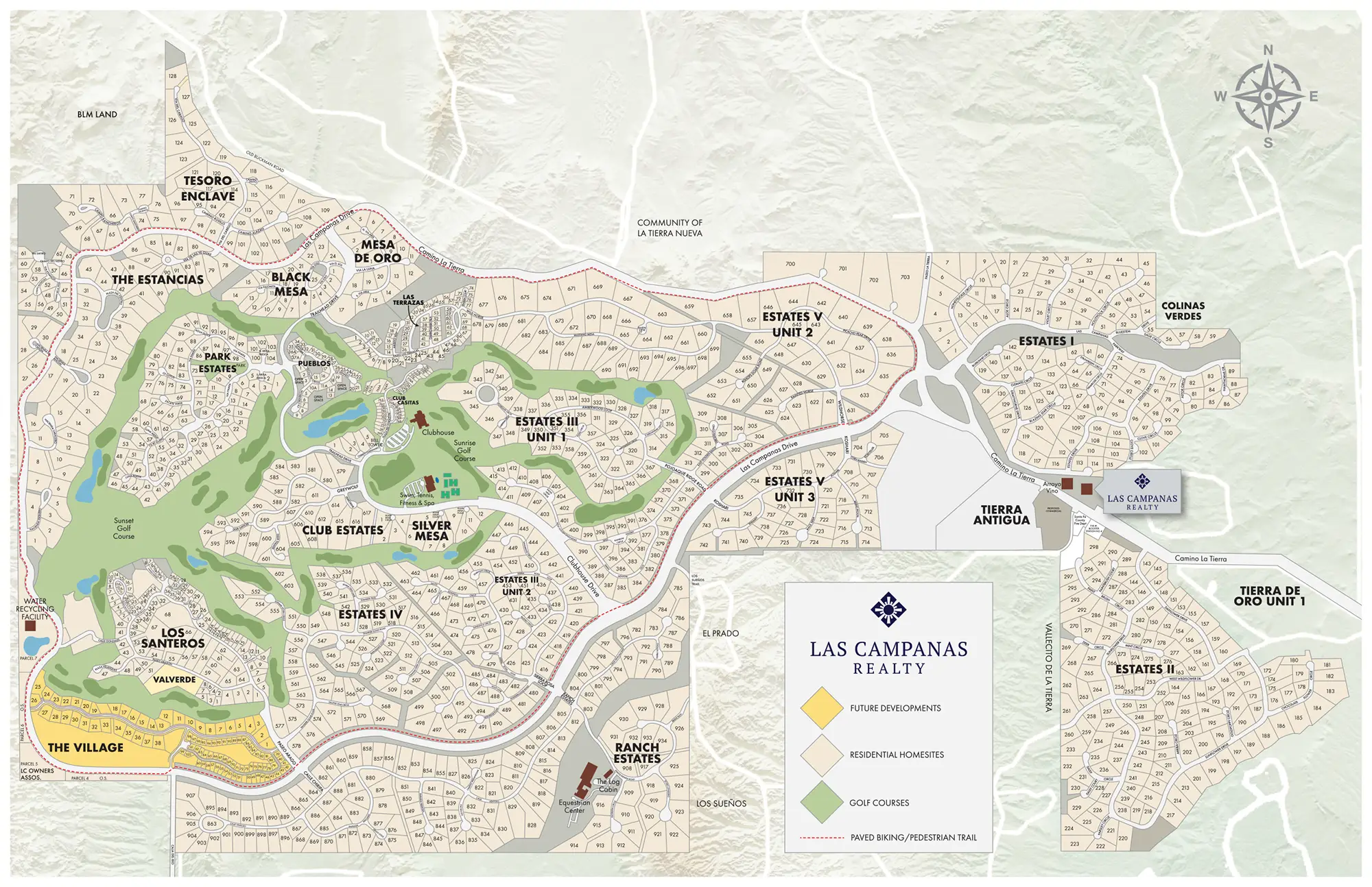 Golf course with sand bunkers and a water hazard, surrounded by houses and trees, with mountains in the background under a blue sky with clouds.