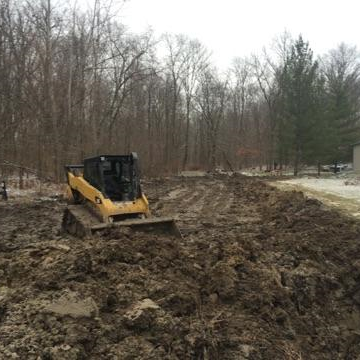 Bobcat laying topsoil in field