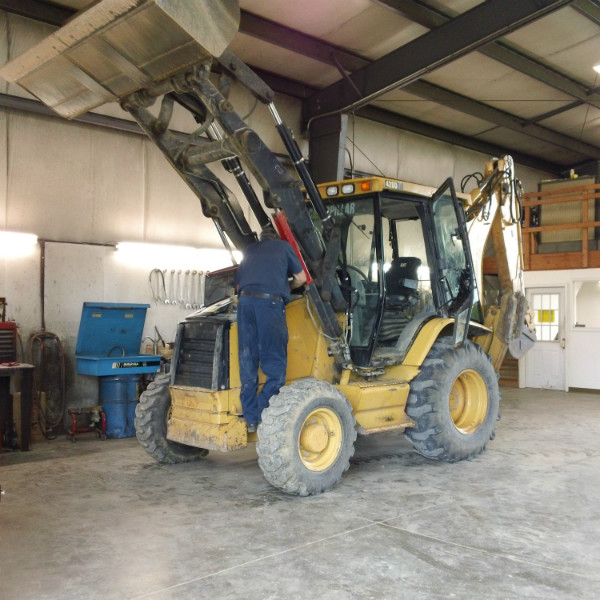Repairman fixing the engine in a backhoe