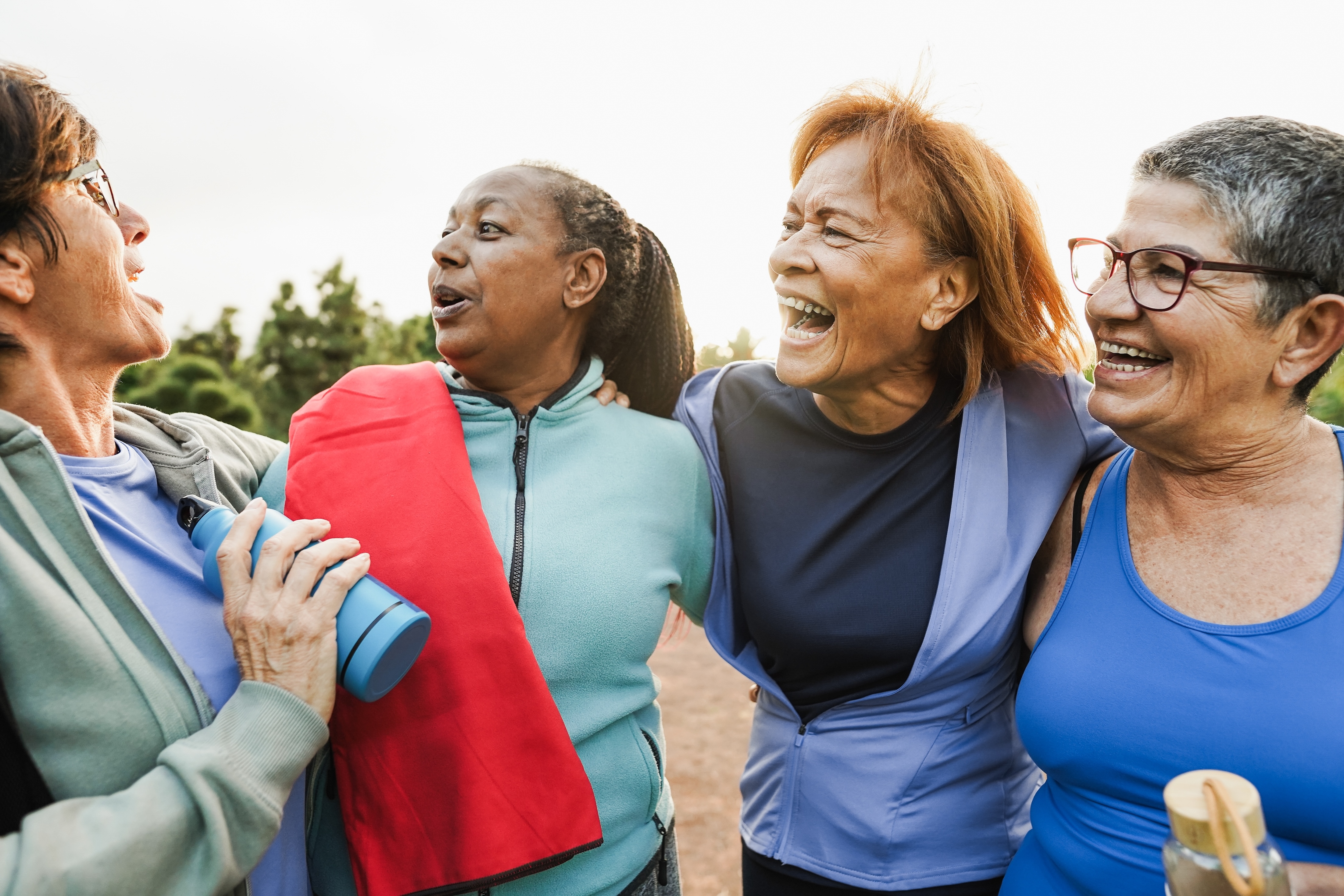 four women smiling with yoga mats outside