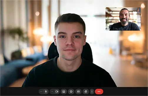 Homme souriant lors d'un appel vidéo avec un autre homme visible dans une petite fenêtre en haut à droite.