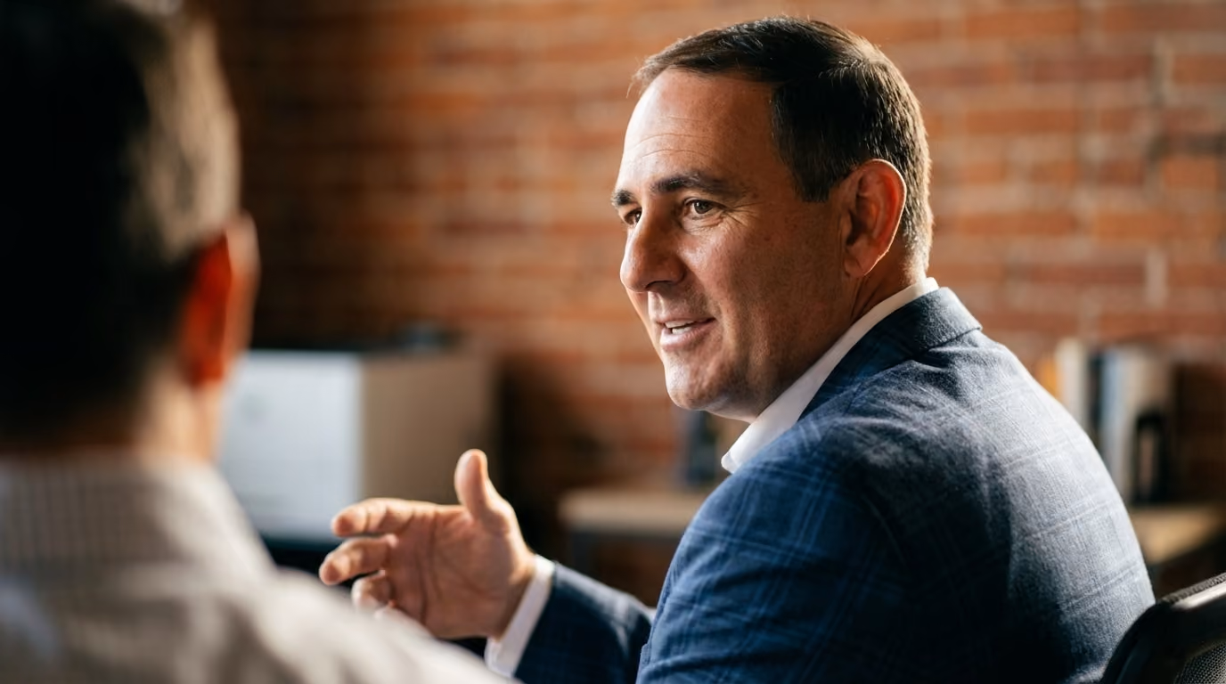A KEPM team member in a blue plaid blazer talking with a client in a brick-walled office