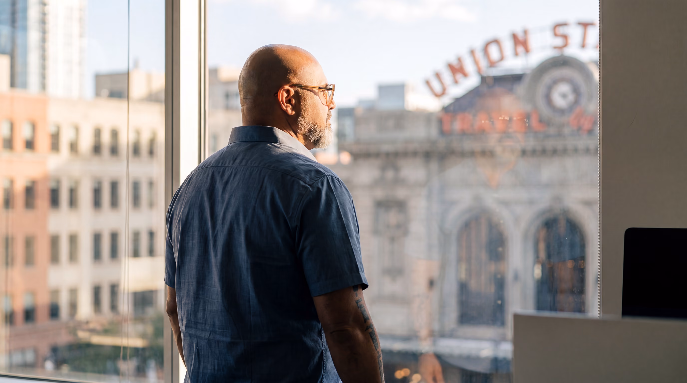 Dr. Kirk Elliott looking out a large office window at a historic city building.